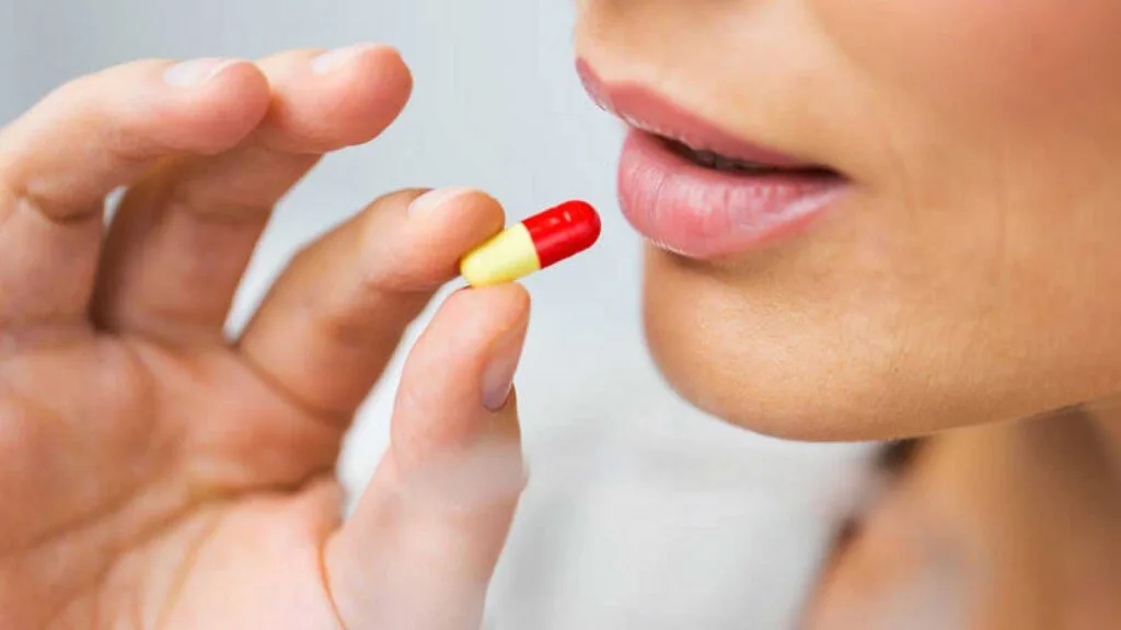 mujer con pastilla para la diabetes en su mano, lista para ingerirla oralmente
